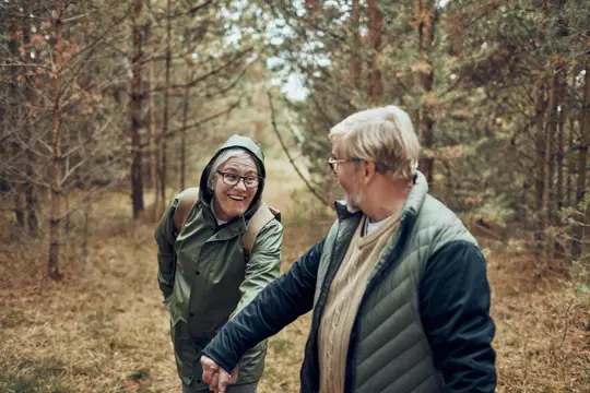 cuplu de pensionari care se plimba in natură în peisaj de toamna
